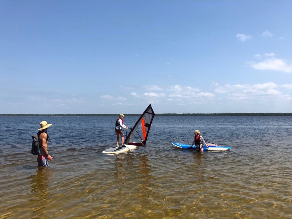 Kinder beim Windsurfen im flachen Wasser